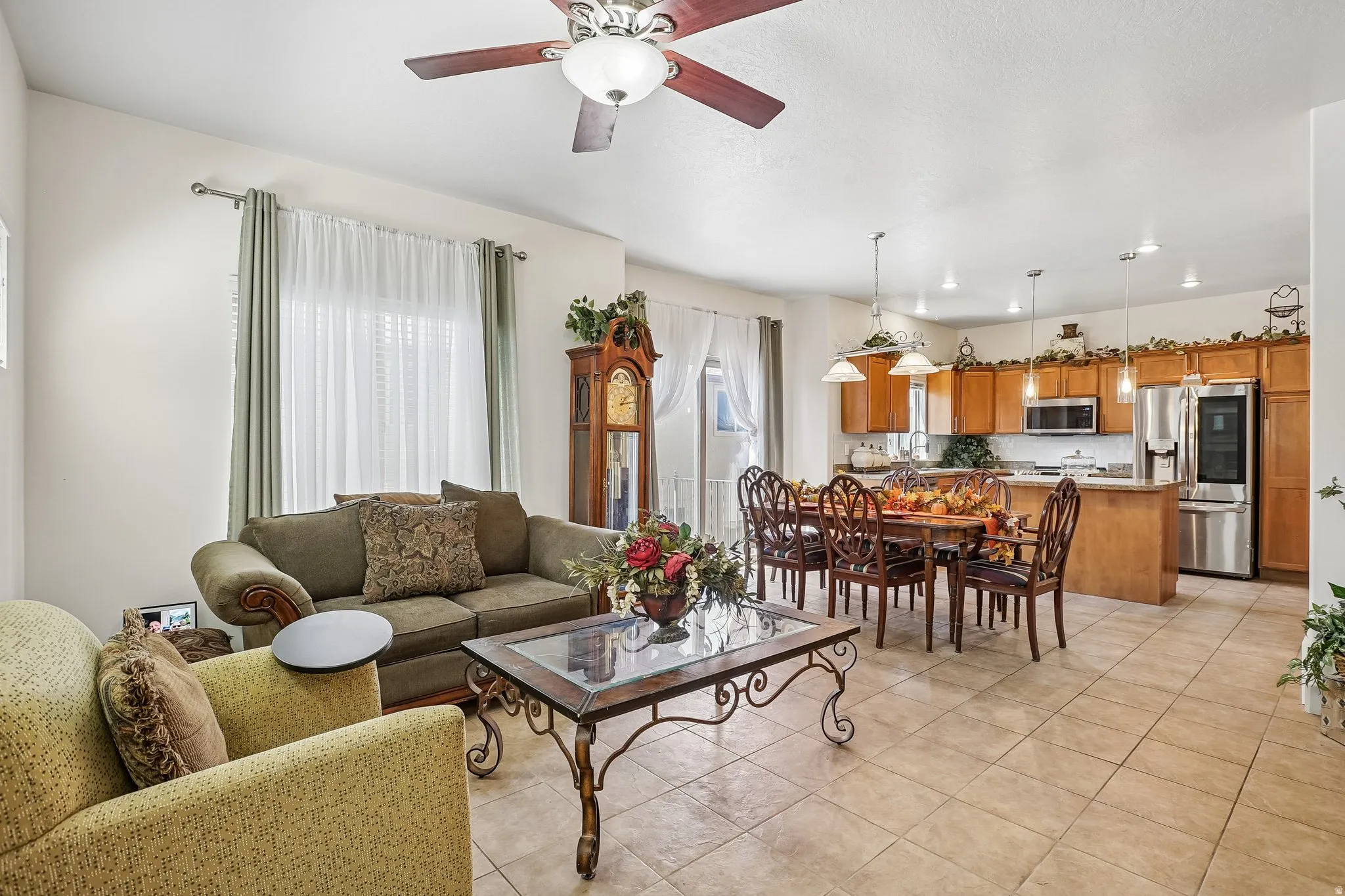 Open-concept living space featuring tile flooring throughout, a kitchen with wood cabinetry and stainless steel appliances, and a dining area with pendant lighting
