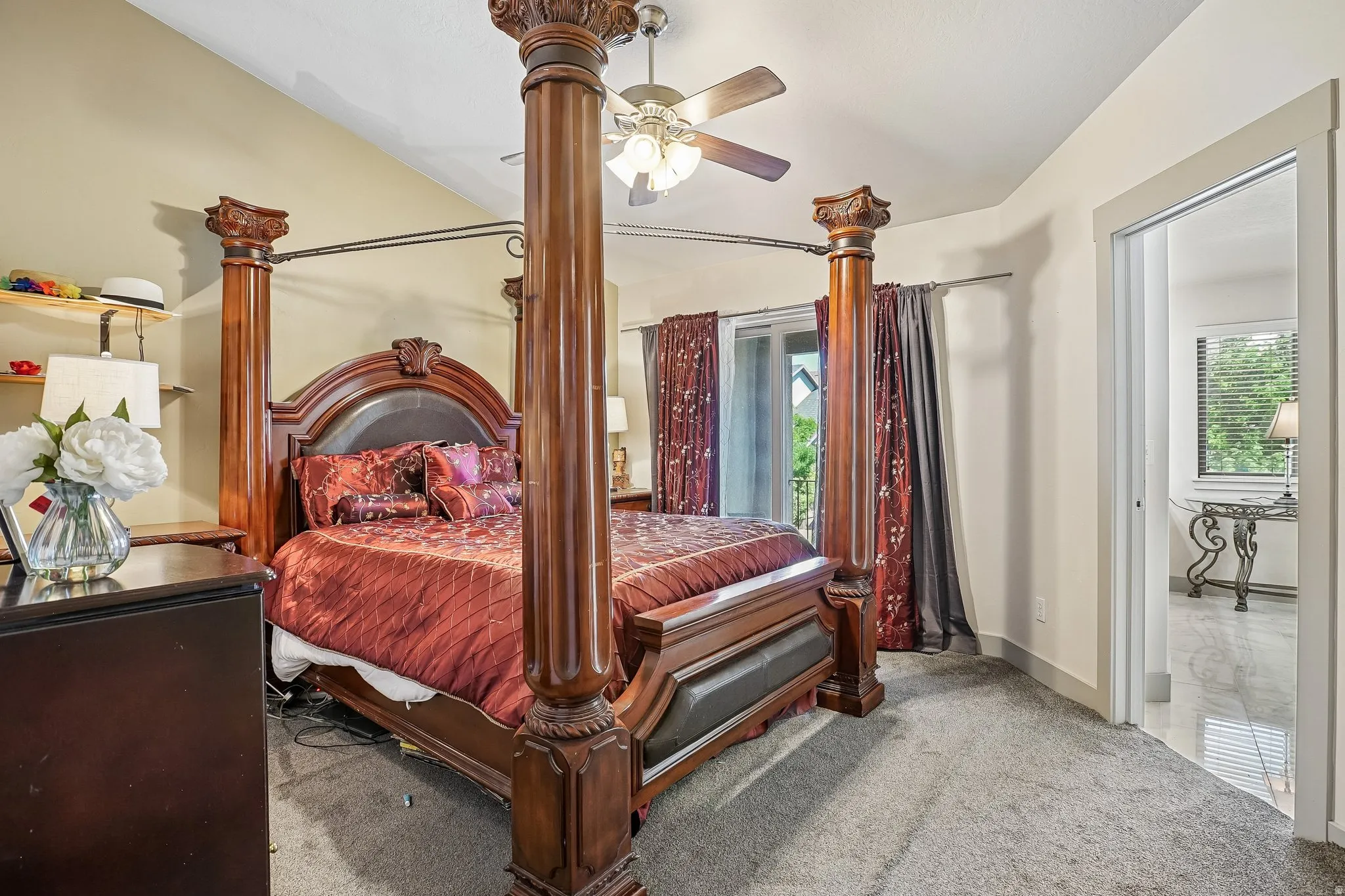 Vaulted ceiling, ceiling fan, carpet flooring, sliding glass door, and interior doorway
