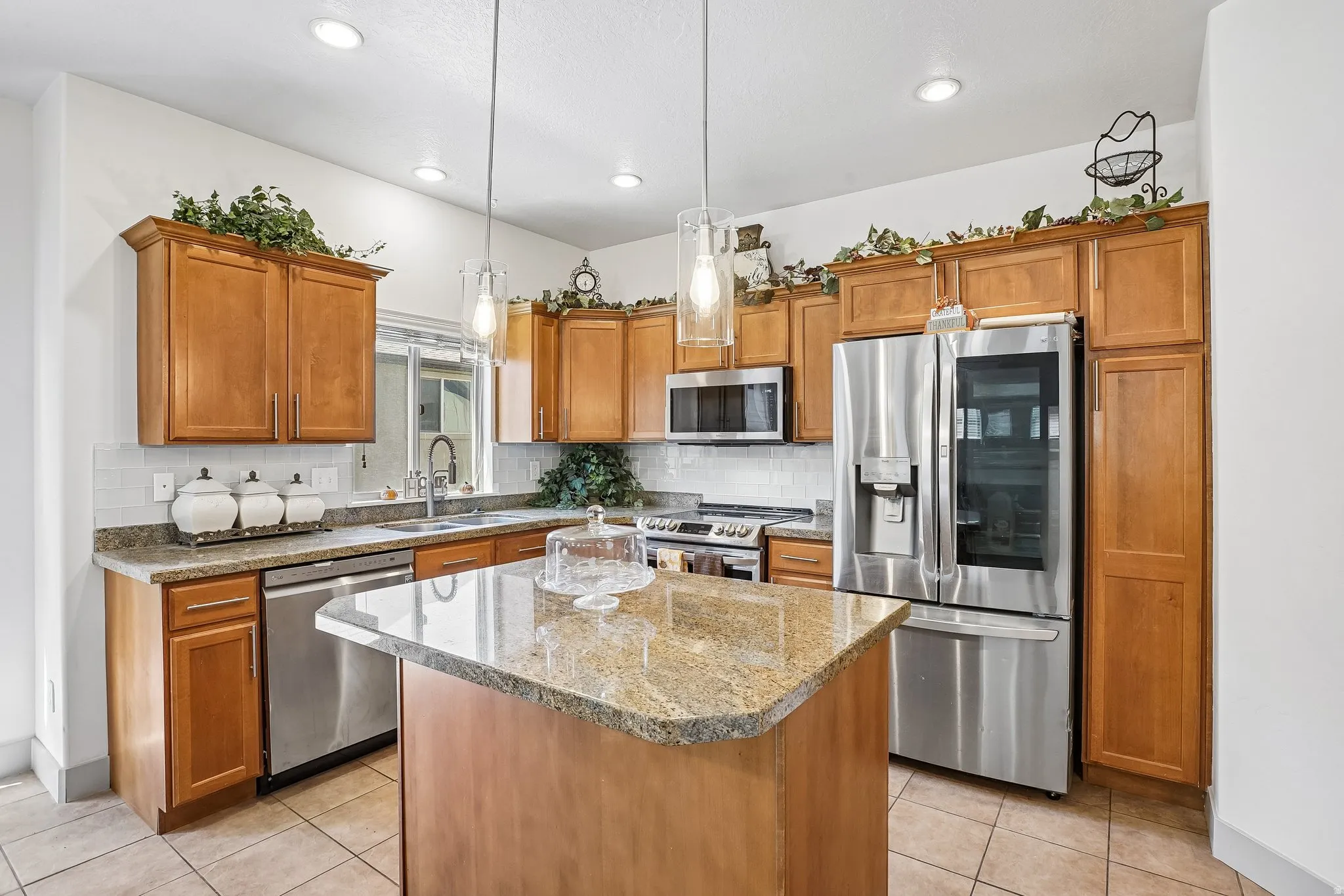 Kitchen featuring a center island with a stone countertop, wood cabinetry, stainless steel appliances, and recessed lighting