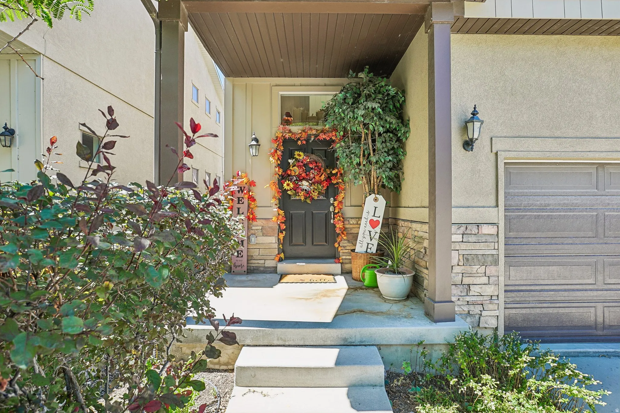 Front entry with concrete steps, stucco and stone veneer facade, and an attached single-car garage