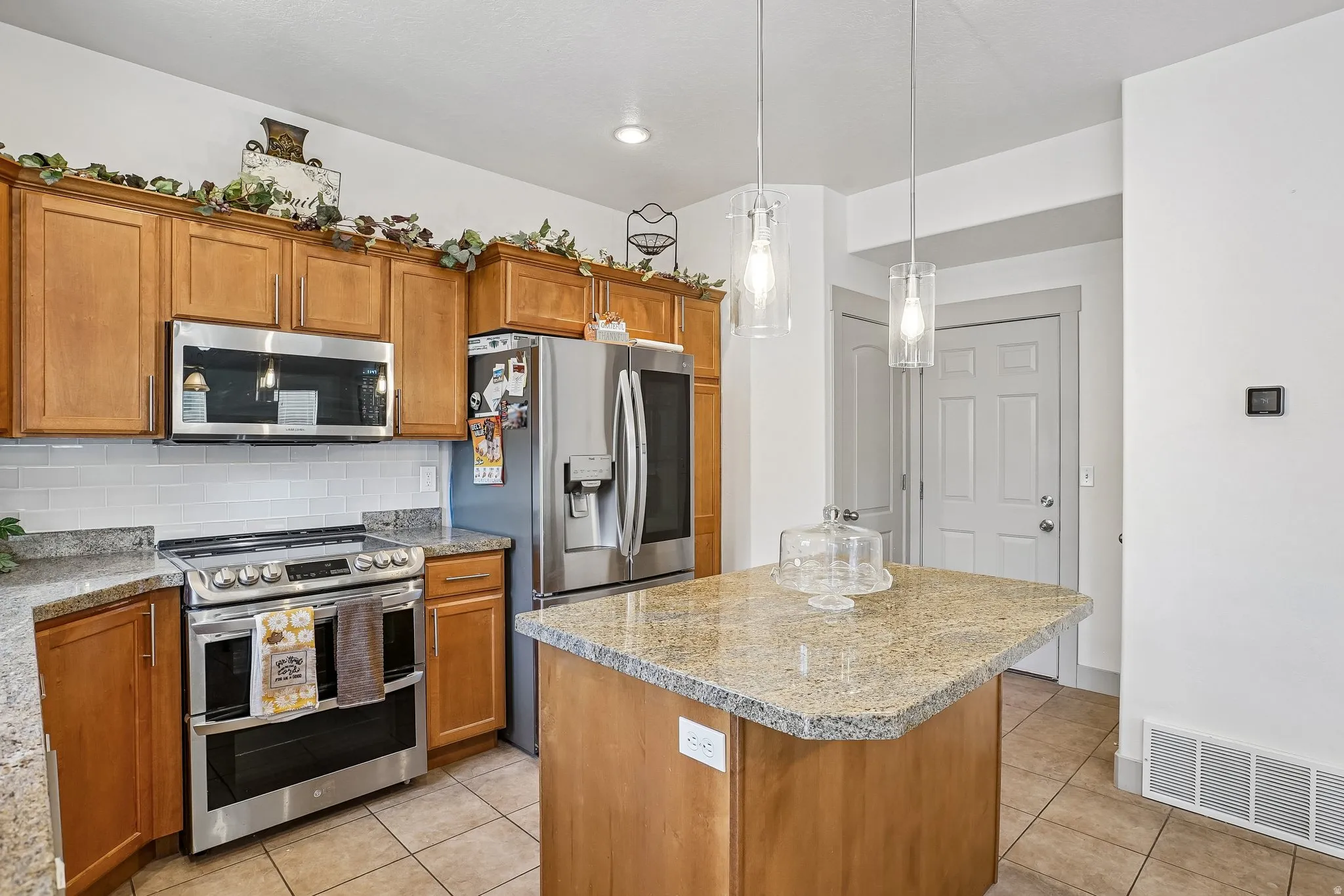 Kitchen featuring wood cabinetry, stainless steel appliances, granite countertops, and a subway tile backsplash