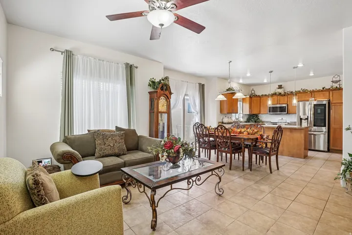 Open-concept living space featuring tile flooring throughout, a kitchen with wood cabinetry and stainless steel appliances, and a dining area with pendant lighting