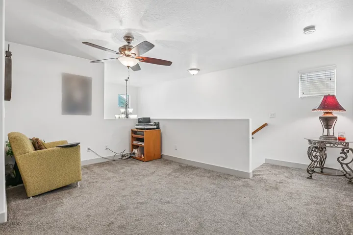 Carpeted living space with a ceiling fan, recessed lighting, and a white interior railing
