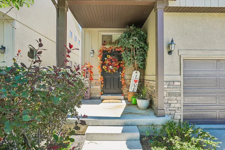 Front entry with concrete steps, stucco and stone veneer facade, and an attached single-car garage