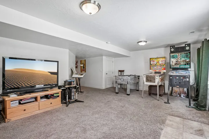 Carpeted floor, recessed ceiling beam, flush-mount lighting, white interior door, and a partially visible tiled area