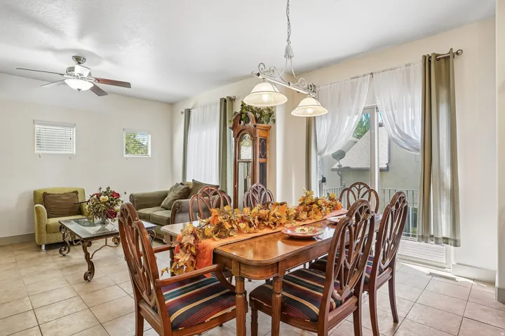 Open concept living and dining area featuring tile flooring, a ceiling fan with integrated lighting, and a sliding glass door leading to an exterior balcony