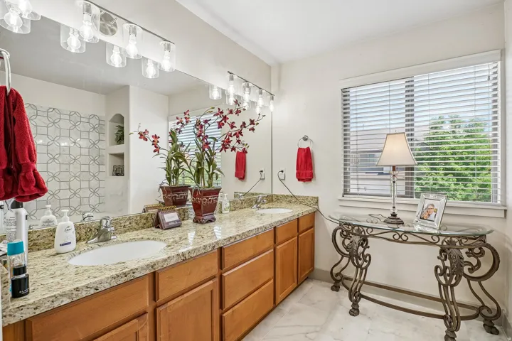 Dual vanity with granite countertops, wood-finish cabinetry, and undermount sinks