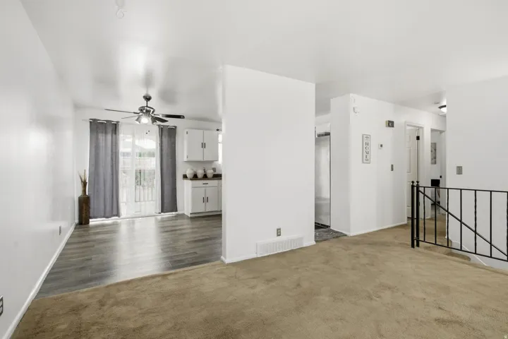 Wood-finish flooring, white cabinetry, ceiling fan, and wrought iron railing