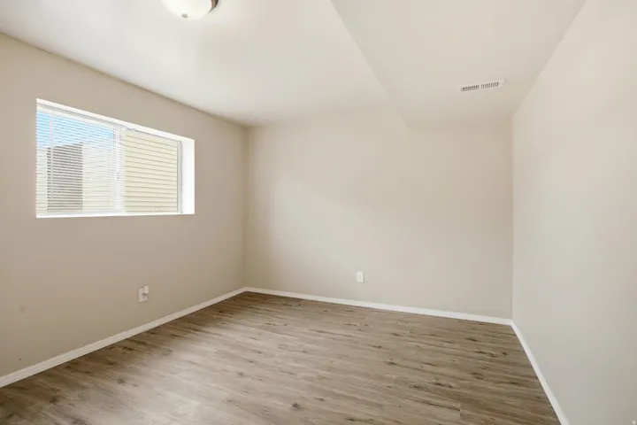 Wood-finish flooring, neutral wall tones, recessed window, and flush mount lighting