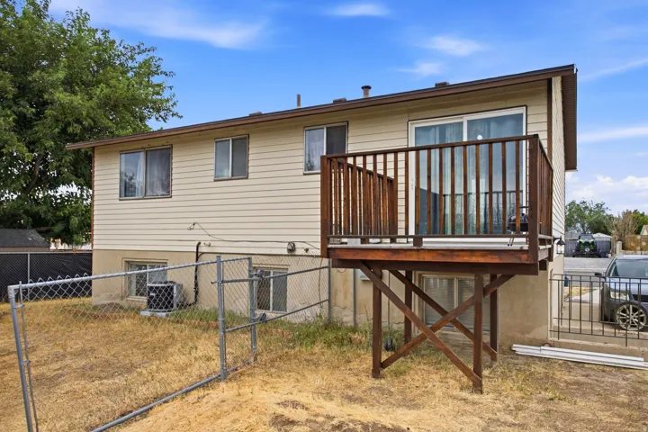 Exterior featuring horizontal siding, a raised wooden deck with railings, sliding glass door access, and a chain-link fence