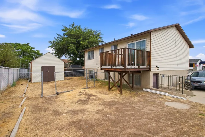 Expansive backyard featuring a detached storage shed, chain-link fencing, and a wooden deck