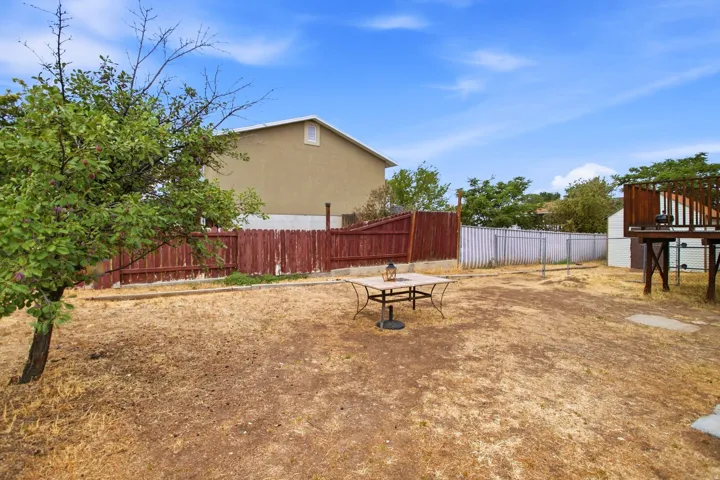 Expansive outdoor space featuring a wood fence, mature tree, and elevated wood deck
