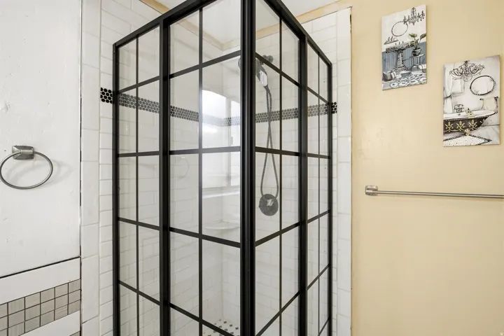 Shower enclosure featuring black-framed glass and white subway tile surround
