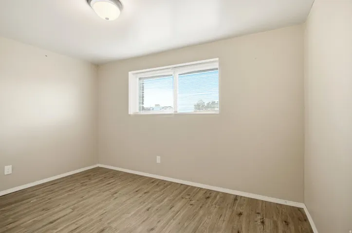 Wood-finish flooring, neutral wall tones, and a window with blinds