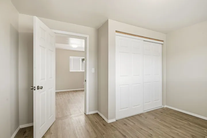 Wood-finish flooring, white paneled door, and a built-in closet with sliding paneled doors