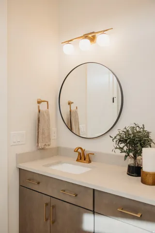 Bathroom vanity with an integrated sink, brushed gold faucet, and light-toned countertop