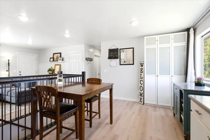 Light wood-finish flooring, built-in cabinetry with frosted glass panels, granite-style countertop, and recessed lighting