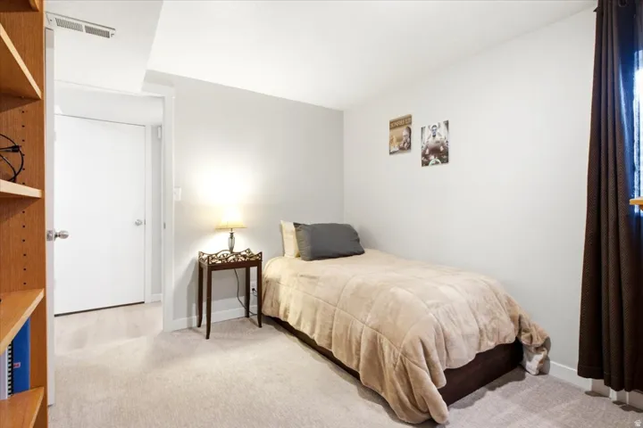 Recessed white door, light-toned wall-to-wall carpeting, wood-finish shelving unit, and white walls