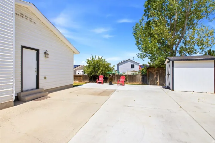 Expansive concrete patio space with a detached storage shed