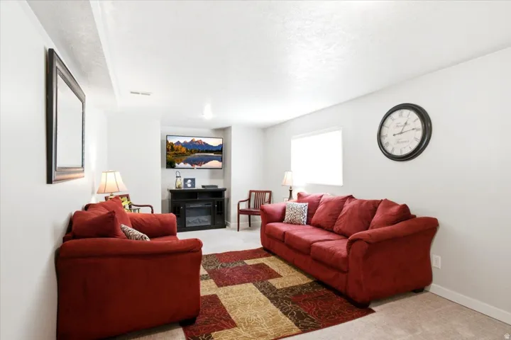 Recessed lighting, light-colored walls, carpeted flooring, built-in media console, and a window for natural light