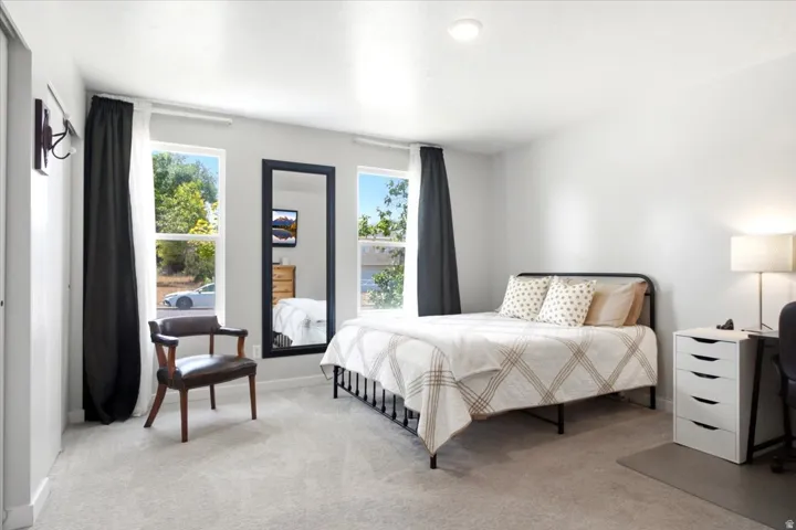 Light gray wall paint, two large windows, recessed ceiling lighting, and light-colored carpeting