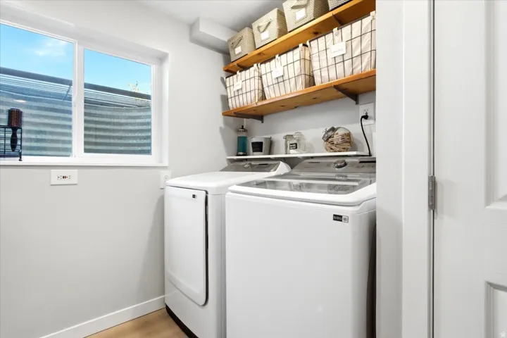 White walls with a window, wood-finish flooring, and built-in wood shelving