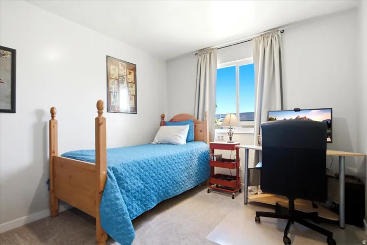 White walls, light-colored carpeting, a window with exterior views, and a desk area