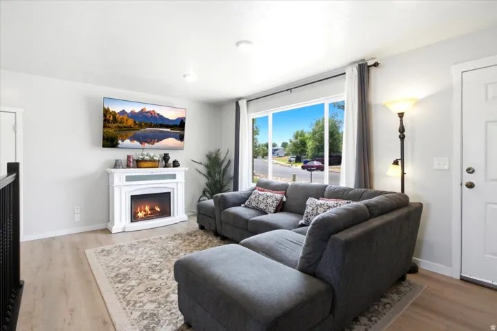 Living space featuring a white fireplace, wood-finish flooring, recessed lighting, and large windows