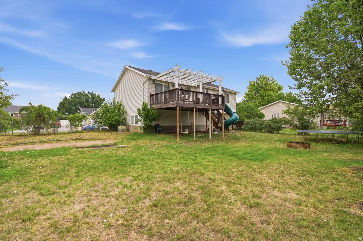 Two-story siding exterior with an elevated wood deck, pergola, and a spacious grassy yard