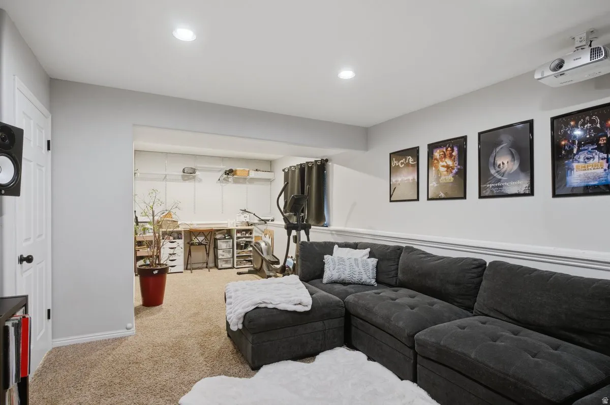 Recessed lighting, wall-mounted projector, wall-mounted speaker, crown molding, and carpeted flooring