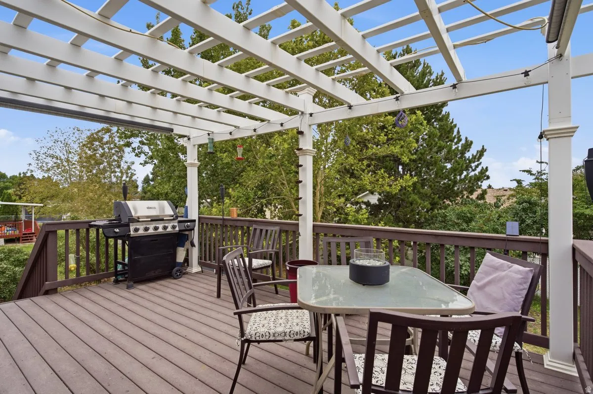 Expansive outdoor deck featuring a white pergola, composite decking, and dark wood railing