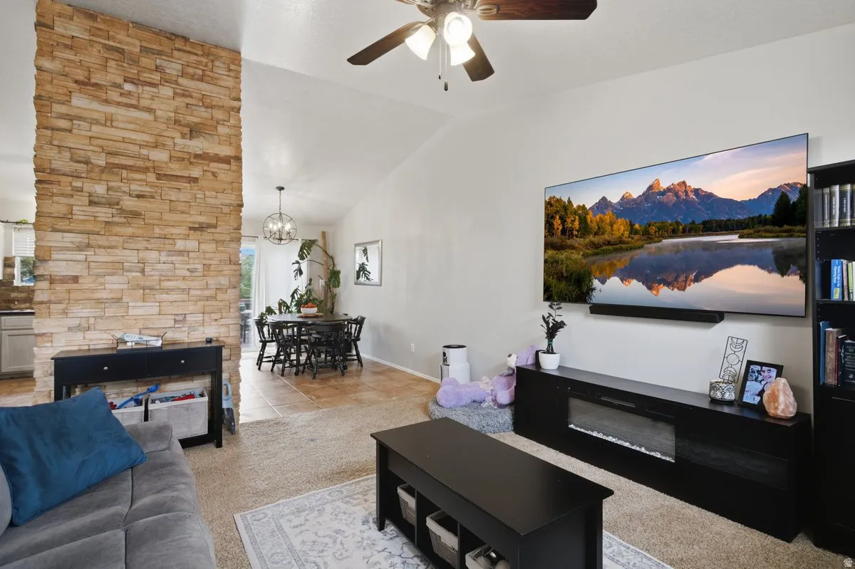 Vaulted ceiling with a ceiling fan, stone accent wall, recessed lighting, and tile flooring