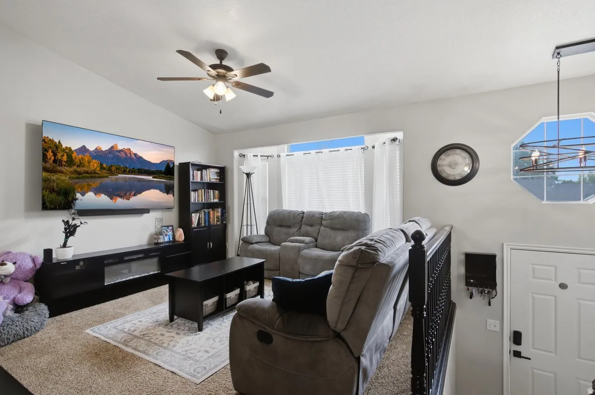 Vaulted ceiling, ceiling fan, carpeted flooring, window with blinds, and white paneled door