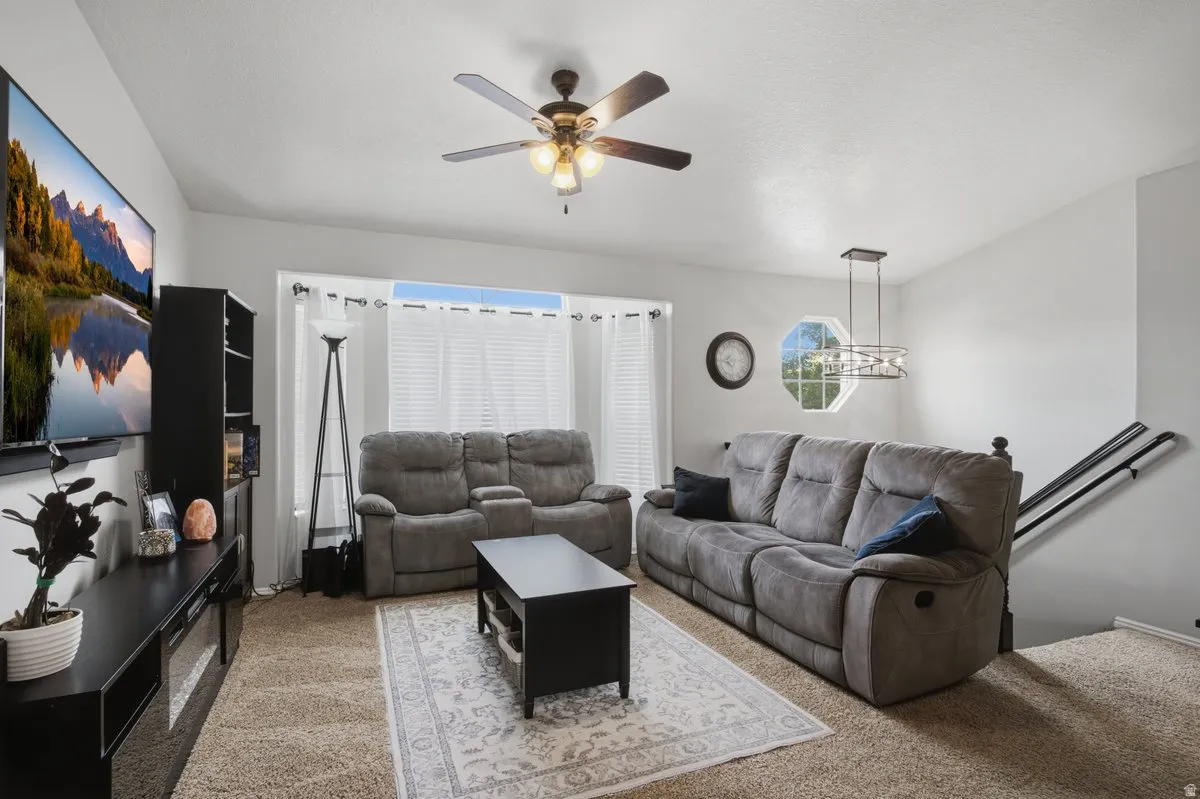 Neutral wall paint, ceiling fan, contemporary chandelier, octagonal window, and carpeted flooring