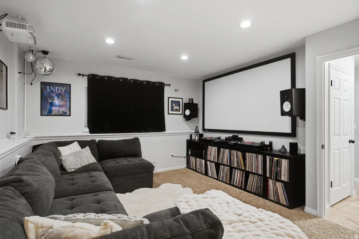 Media room featuring a large projection screen, built-in media console, recessed lighting, and carpet flooring