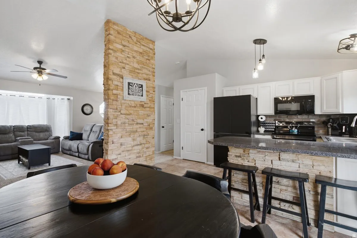 Kitchen featuring white cabinetry, dark countertops, and black appliances