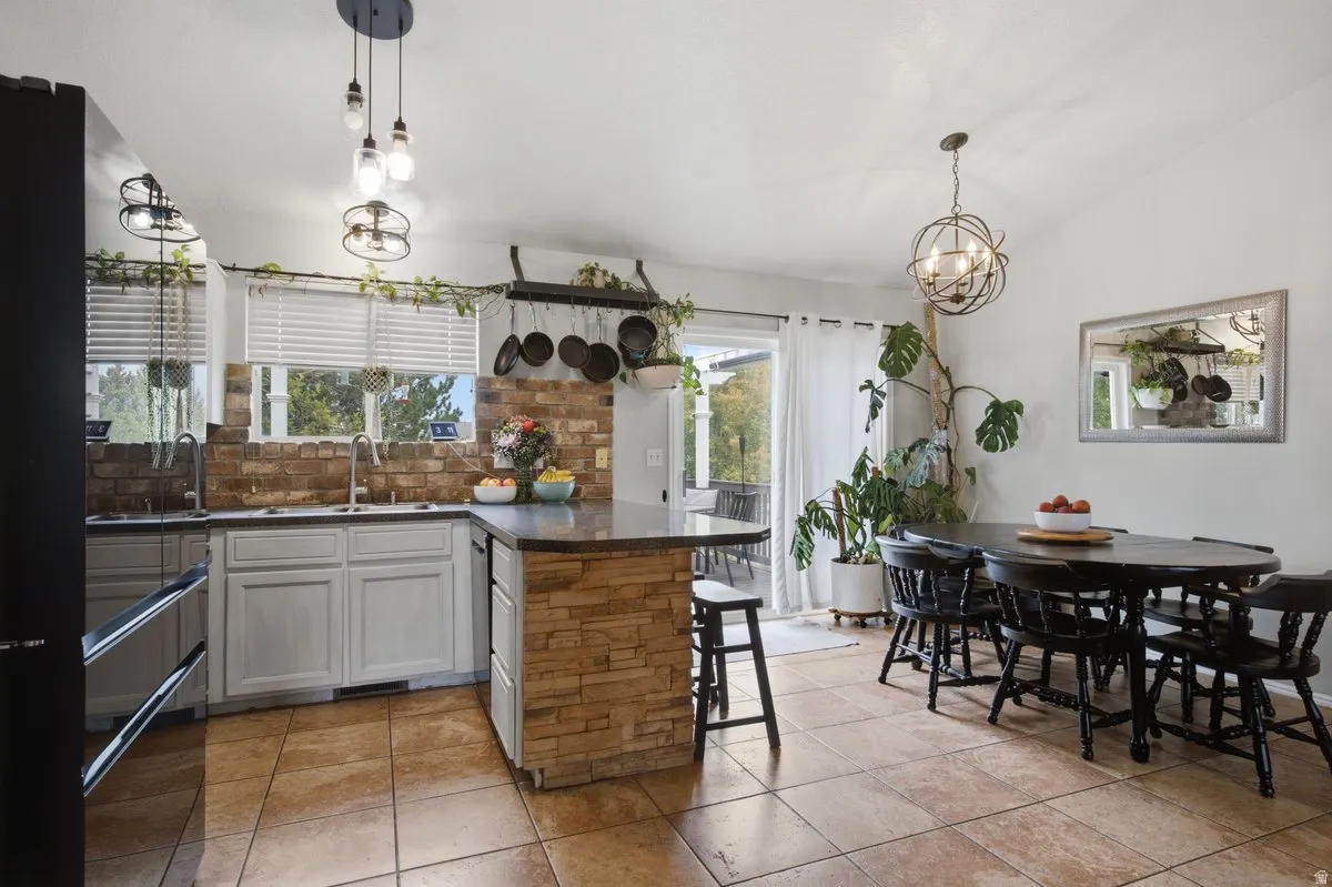 Kitchen with stone veneer island base, L-shaped cabinetry, and a brick-finish backsplash