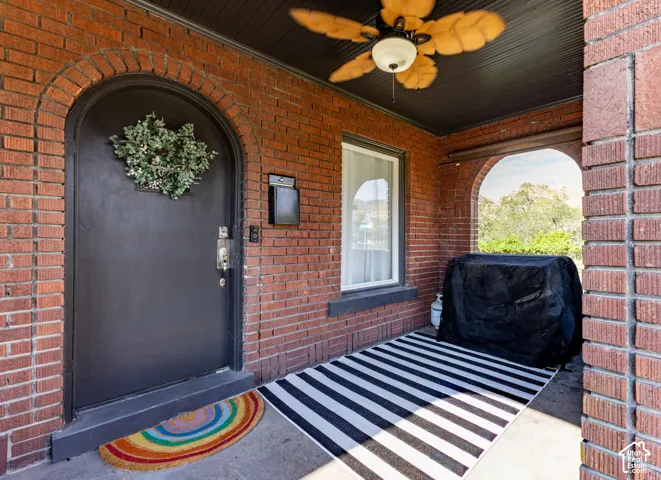 Brick exterior entry with arch, dark front door, and a built-in ceiling fan
