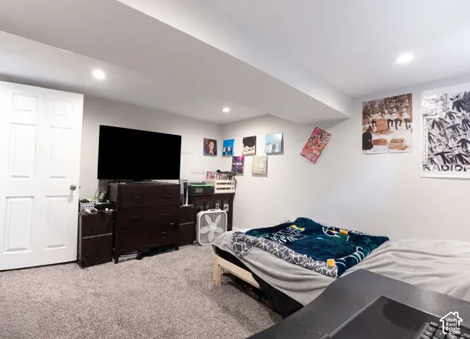 Recessed lighting illuminates the space, featuring light gray walls and plush gray carpeting