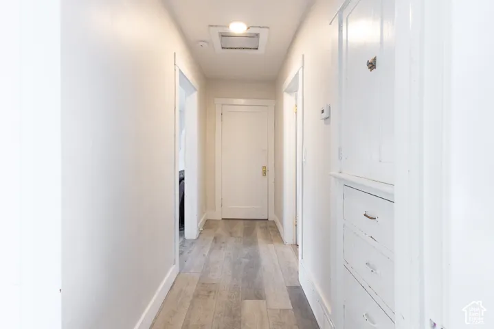 Hallway featuring wood-finish flooring, built-in cabinetry, and recessed lighting
