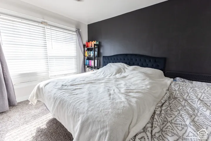 Wall-to-wall carpeting and a dark accent wall with a large window