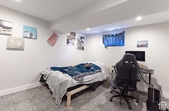 Recessed lighting illuminates the space, featuring light gray walls and gray carpeting