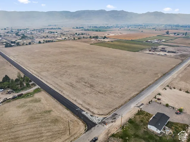 Expansive land parcel featuring clear terrain, paved road frontage, and distant mountain scenery