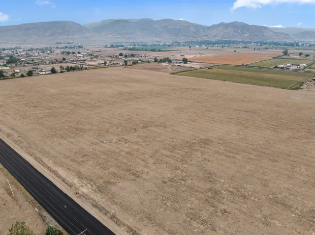 Expansive open land with a paved road, mountainous backdrop, and distant structures