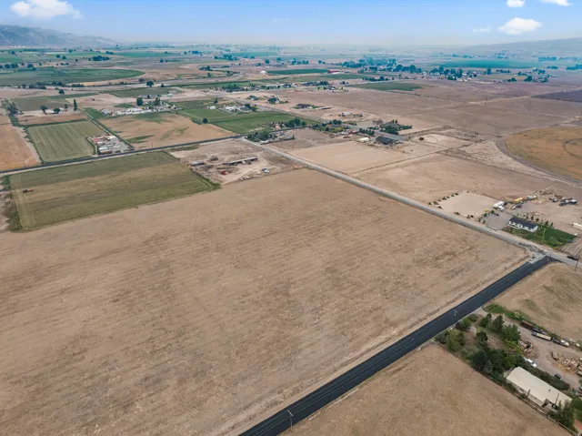 Expansive undeveloped land parcels with agricultural fields, bordered by paved roadways