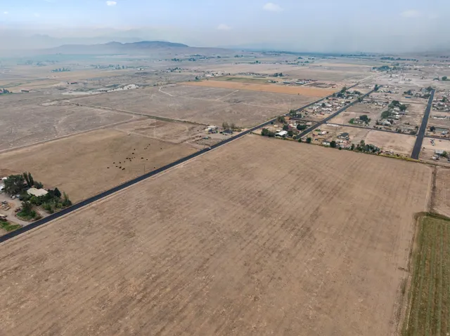 Expansive agricultural land featuring a paved road and distant mountainous terrain