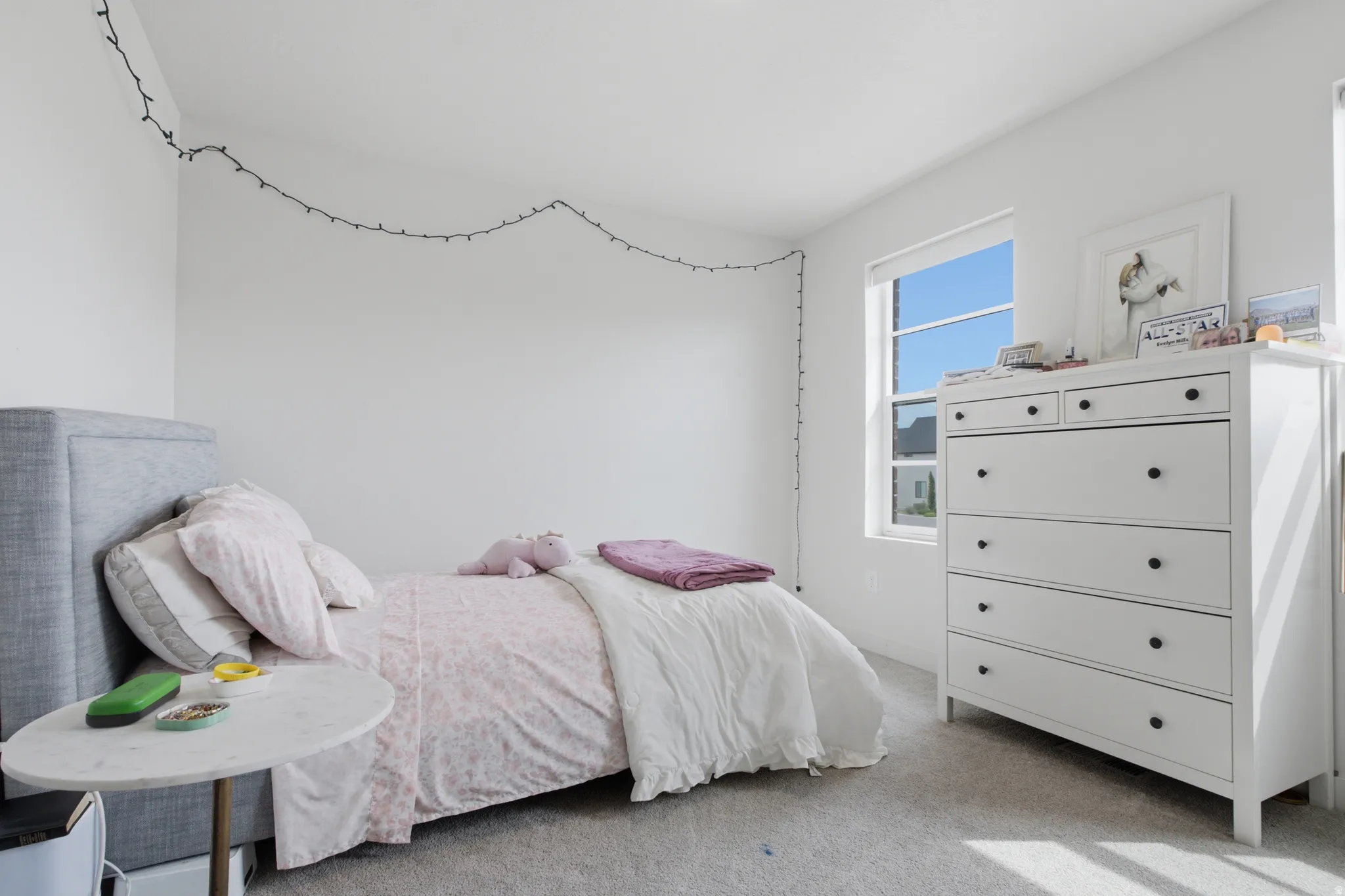 White walls, carpeted flooring, and a large window providing natural light