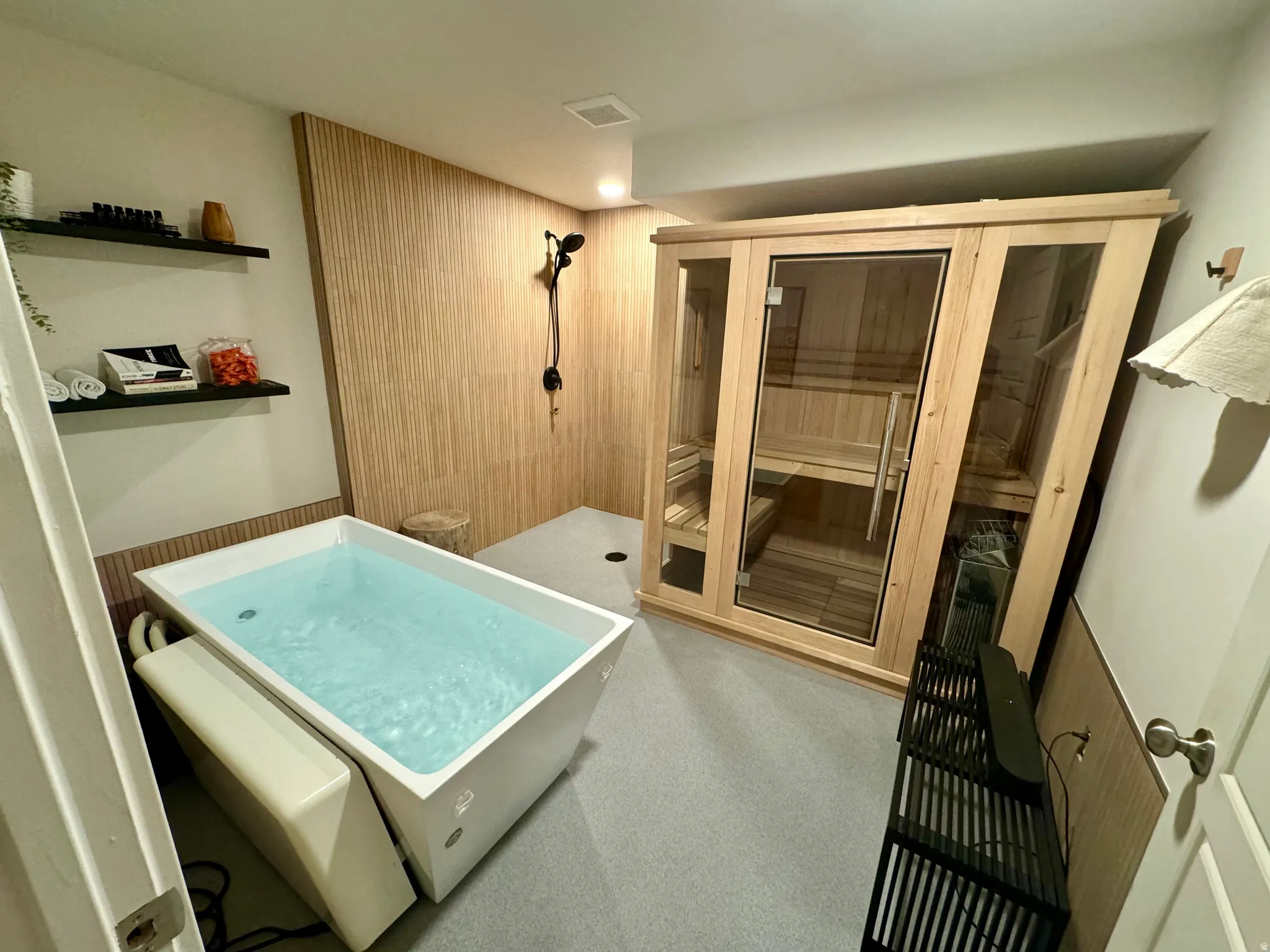 Plunge tub, dedicated shower area with wood paneling, and a built-in sauna featuring a glass door