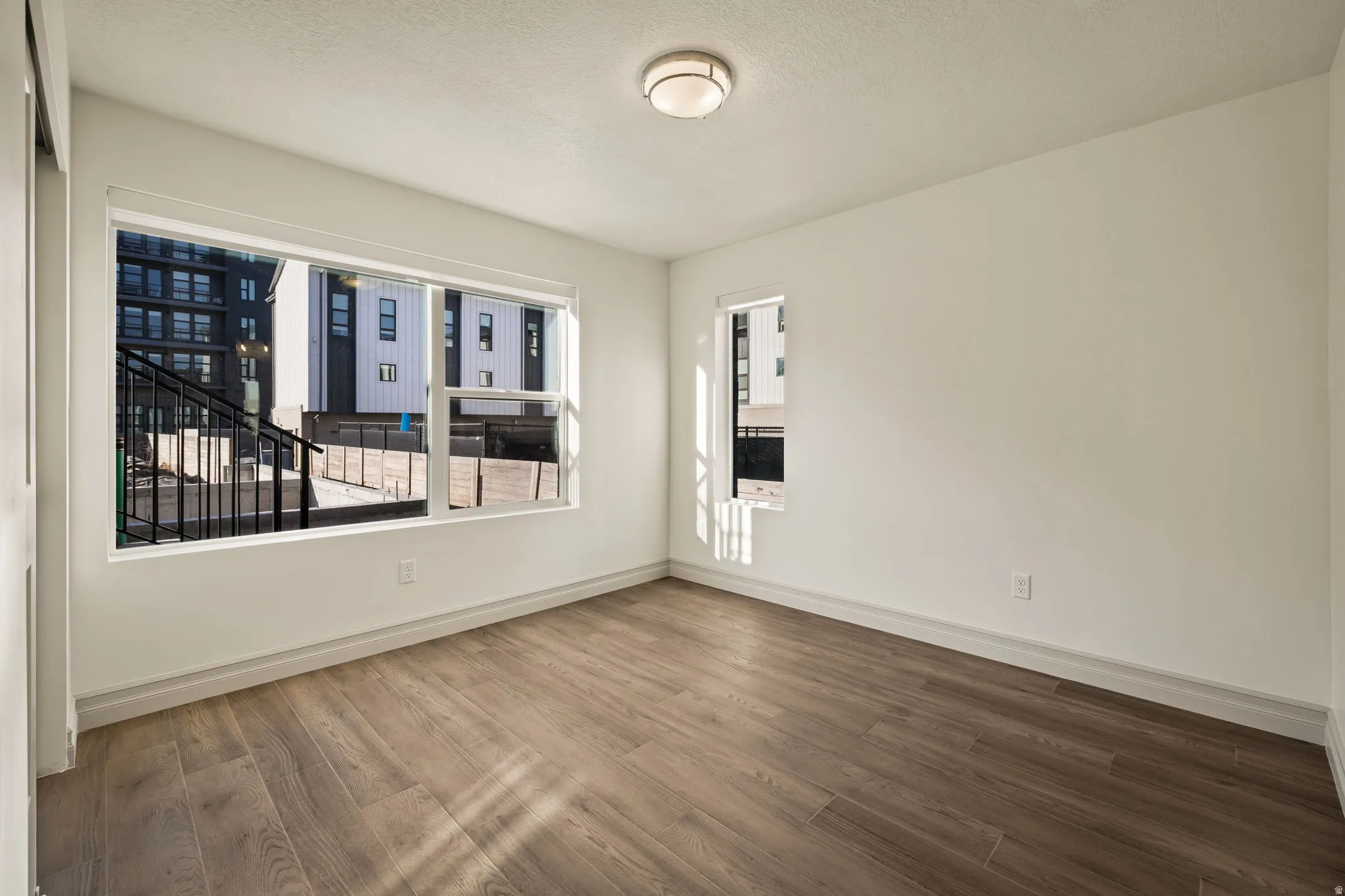 Wood-finish flooring, white painted walls, and a flush mount ceiling light