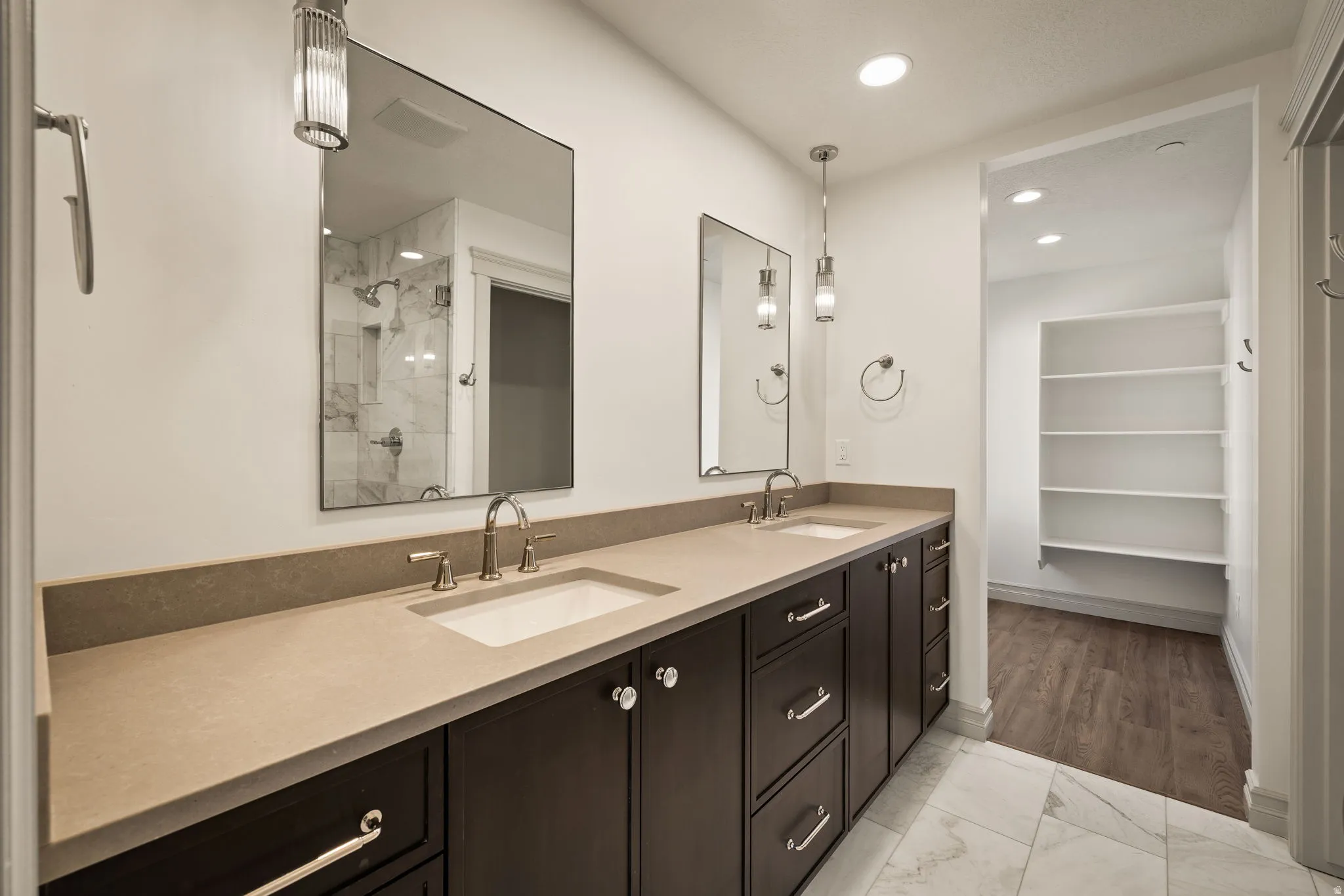 Dual vanity with integrated sinks, stone-finish countertop, dark wood-finish cabinetry, and contemporary pendant lighting